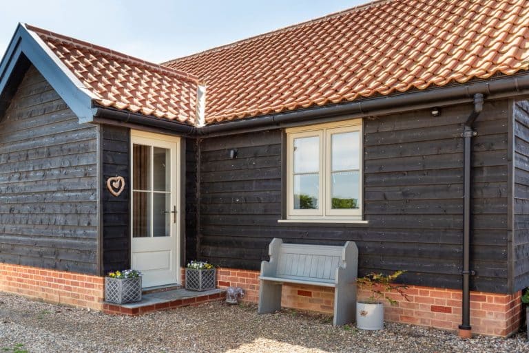Thermally efficient timber flush casement windows in french grey and matching entrance door with 18mm glazing bars