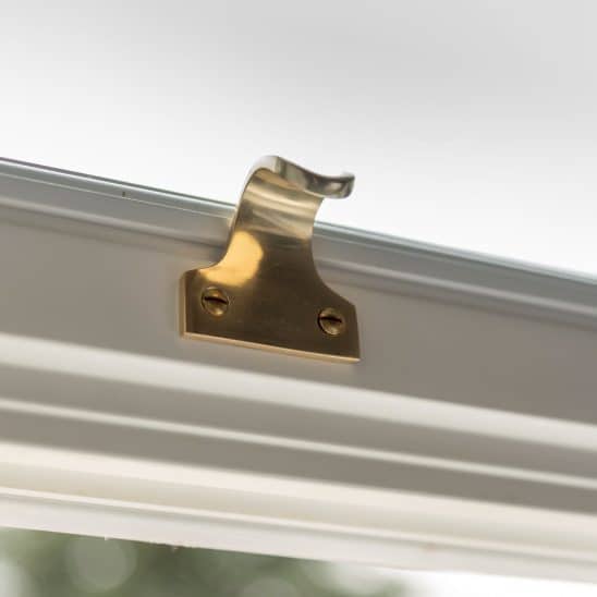 Polished brass sash lift on white slim timber sash window