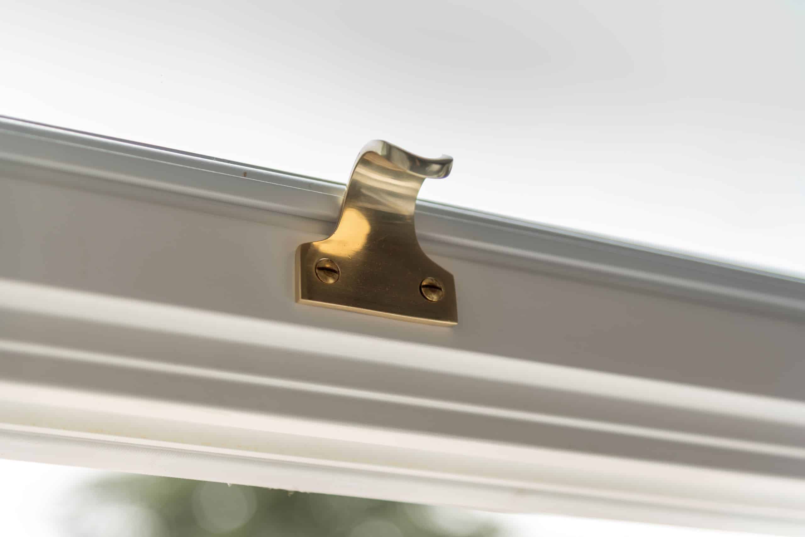 Polished brass sash lift on white slim timber sash window
