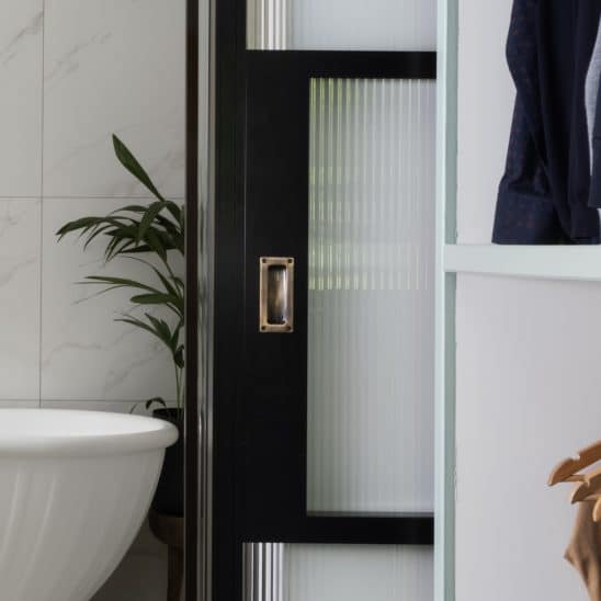 Aluco internal sliding door with steel look glazing bars, reeded glass and antique brass sliding door handle