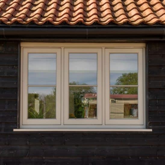 Flush casement timber windows with a single 18mm astragal bar against black timber cladding