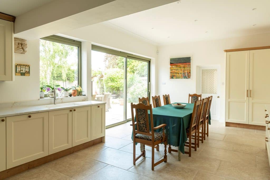 Country kitchen with green slimline sliding doors and matching green aluminium window. 
