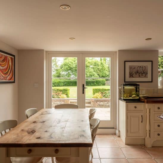 Engineered timber French doors with a cottage black handle and 18mm glazing bars in off white, and Evolution flush casement windows with black monkeytail handles in white.