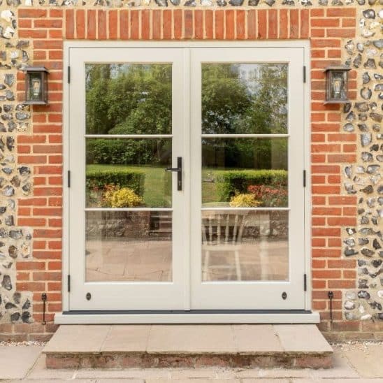 Engineered timber French doors with a cottage black handle and 18mm glazing bars in French Grey with Evolution PVCu flush casement windows with a single horizontal Georgian bar in Olive Grey.
