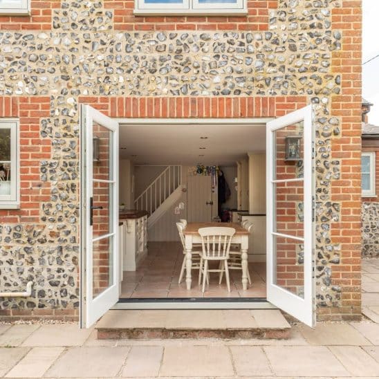 Engineered timber French doors with a cottage black handle and 18mm glazing bars in French Grey with Evolution PVCu flush casement windows with a single horizontal Georgian bar in Olive Grey.