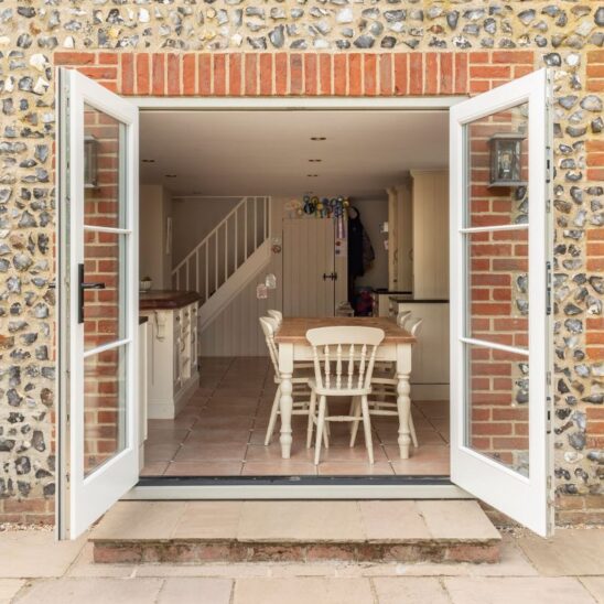 Engineered timber French doors with a cottage black handle and 18mm glazing bars in French Grey with Evolution PVCu flush casement windows with a single horizontal Georgian bar in Olive Grey.