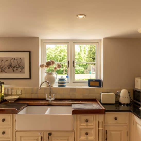 Evolution PVCu flush casement window with a single horizontal Georgian bar and black monkeytail handles. Olive Grey on the outside, white on the inside.