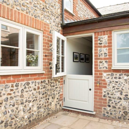Evolution PVCu flush casement windows with a single horizontal Georgian bar in Olive Grey and engineered timber 'Stratfield' stable door with cottage black handle and 18mm glazing squares, in French Grey.