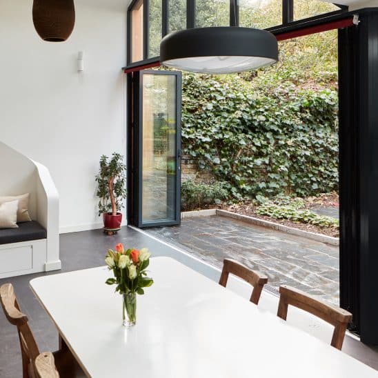 Open bifold doors with matching single door inside a dining room and patio area