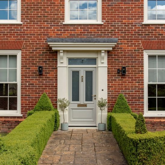 Timber Westonbirt engineered timber entrance door in Porcelain, with aged brass Newbury door handle, Doctor's door knocker and traditional letterbox