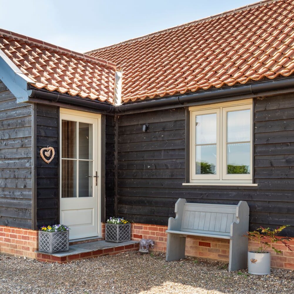 Thermally efficient timber flush casement windows in french grey and matching entrance door with 18mm glazing bars